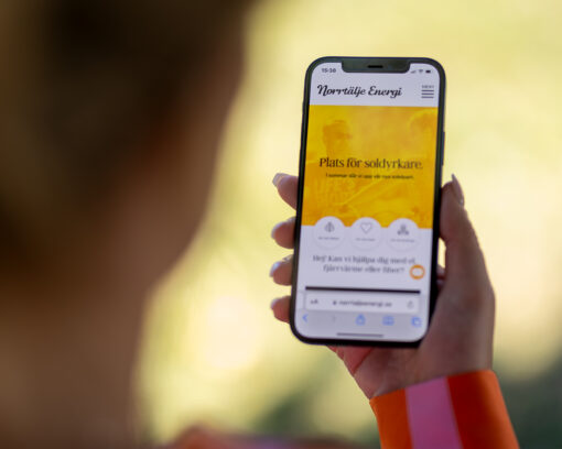 En extrem närbild på en person som håller i en smart telefon och är inloggad på Norrtäljeenergi.se.